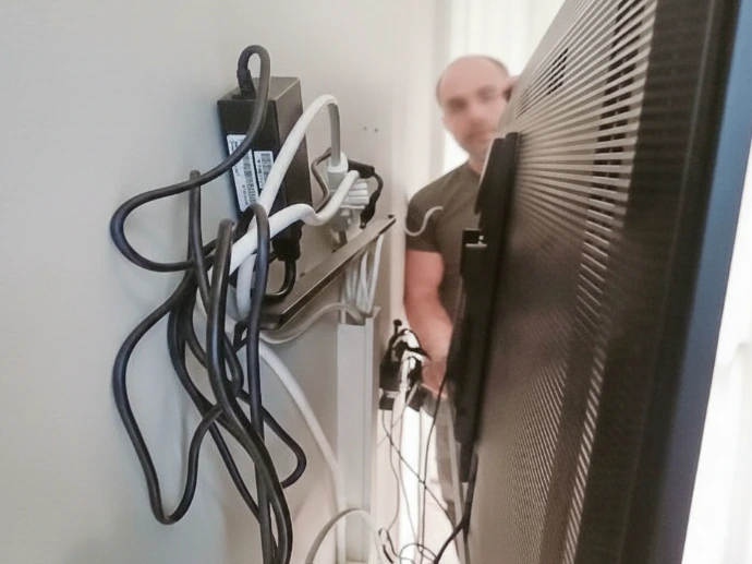 Rörig kabelinstallation bakom skärm i mötesrum